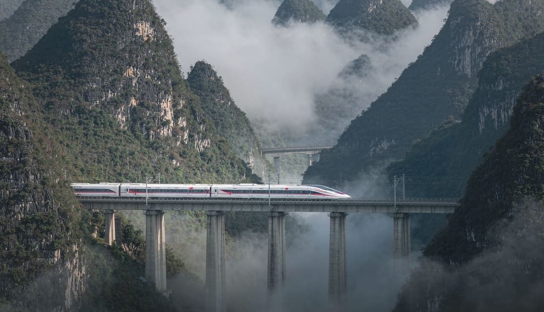 Tren de alta velocidad cruzando un viaducto entre montañas kársticas