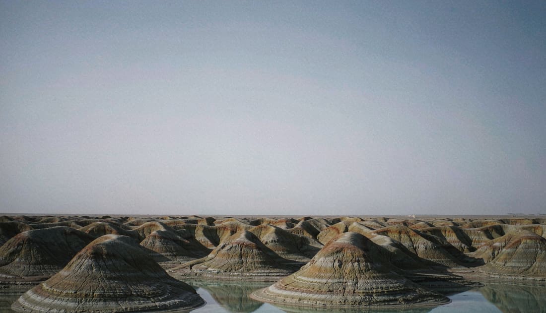 Crestas de yardang emergiendo de agua turquesa en un entorno árido